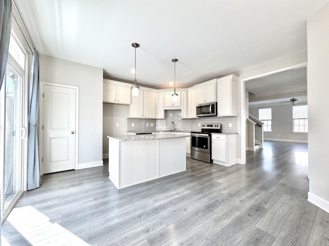 kitchen featuring a sink, white cabinetry, light wood-style floors, appliances with stainless steel finishes, and decorative backsplash