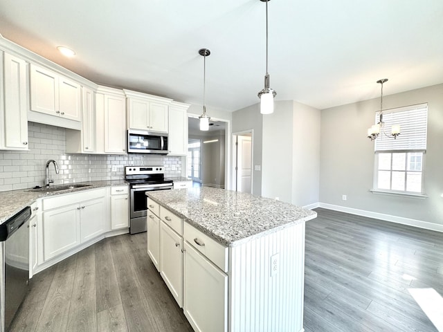 kitchen featuring appliances with stainless steel finishes, backsplash, a sink, and wood finished floors