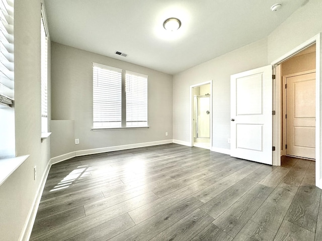 unfurnished room featuring dark wood-style floors, visible vents, and baseboards