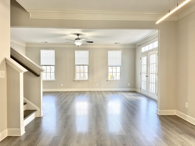 unfurnished living room with dark wood-type flooring, french doors, ornamental molding, and stairway