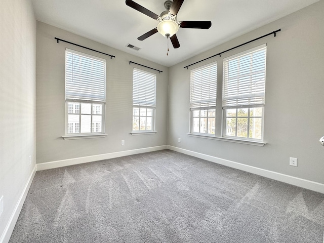 carpeted empty room with baseboards, visible vents, and a ceiling fan