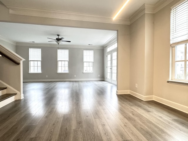 unfurnished living room with ceiling fan, dark wood-type flooring, baseboards, stairs, and ornamental molding