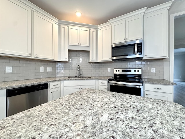 kitchen with appliances with stainless steel finishes, a sink, white cabinetry, and decorative backsplash