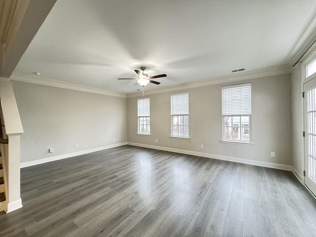 empty room featuring visible vents, dark wood-type flooring, and ornamental molding