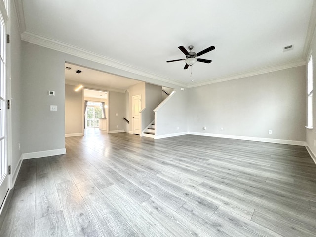 unfurnished living room with wood finished floors, visible vents, baseboards, stairs, and crown molding