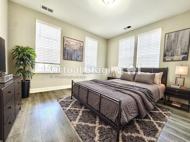 bedroom featuring wood-type flooring, visible vents, and baseboards