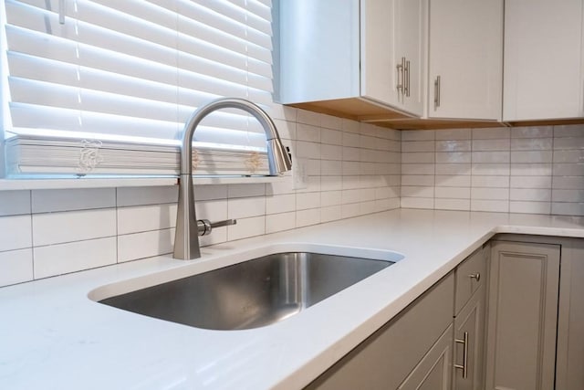 interior details featuring tasteful backsplash, light countertops, and a sink