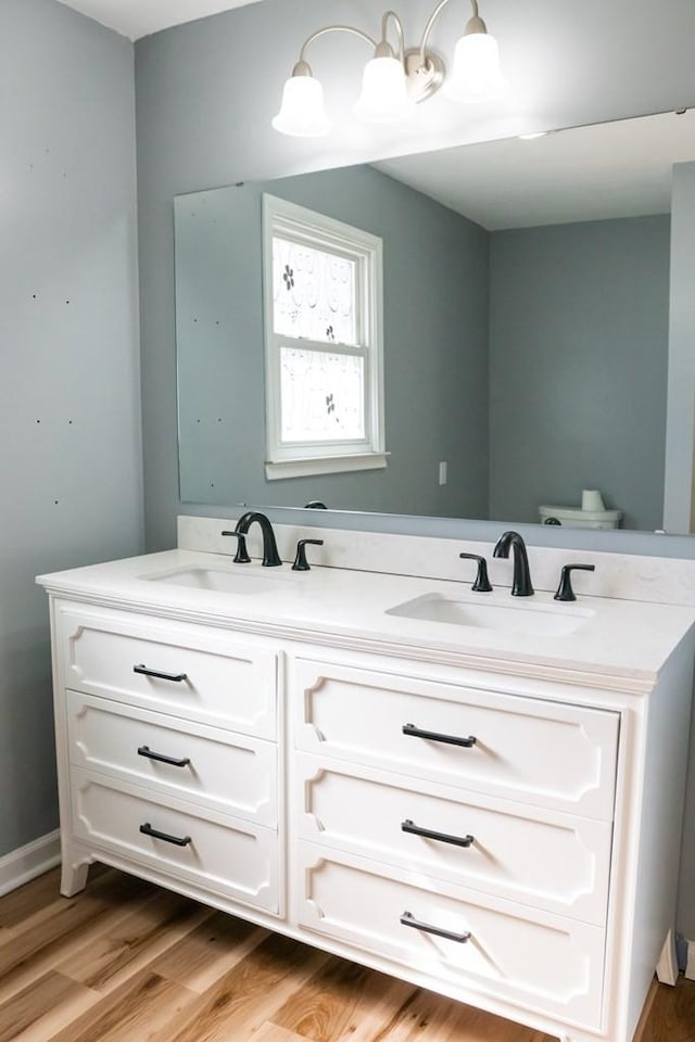 bathroom featuring double vanity, a sink, and wood finished floors