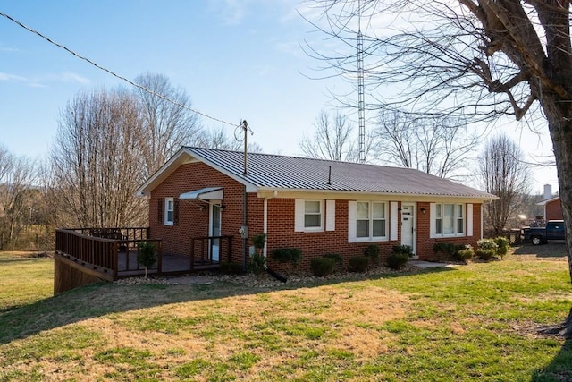 view of front of home with a deck, metal roof, brick siding, a standing seam roof, and a front yard