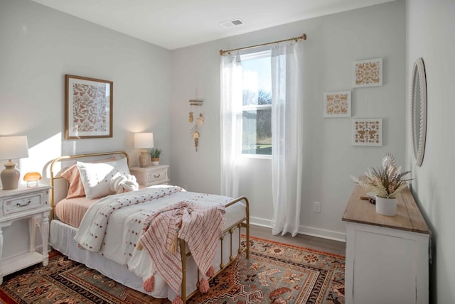 bedroom featuring wood finished floors, visible vents, and baseboards