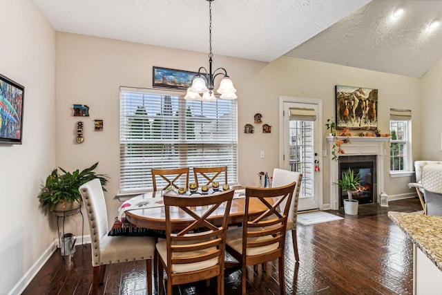 dining area featuring dark wood-type flooring, a tile fireplace, a textured ceiling, and baseboards