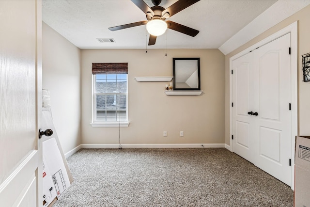 unfurnished bedroom featuring a textured ceiling, carpet floors, visible vents, and baseboards