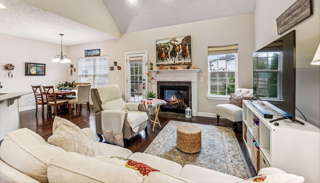 living area featuring baseboards, dark wood finished floors, lofted ceiling, a textured ceiling, and a fireplace