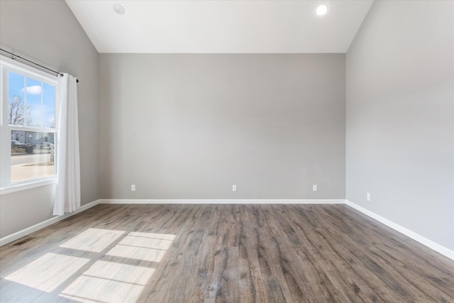 empty room featuring lofted ceiling, recessed lighting, baseboards, and wood finished floors