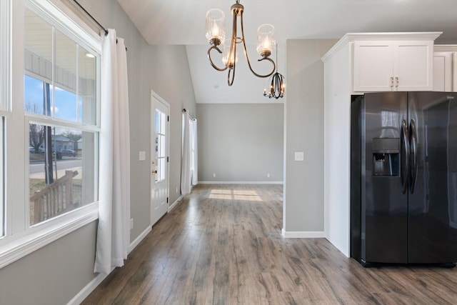 interior space featuring a chandelier, wood finished floors, baseboards, white cabinets, and black refrigerator with ice dispenser