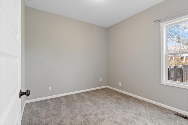 carpeted spare room with visible vents and baseboards