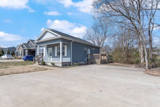 view of side of home featuring covered porch and concrete driveway