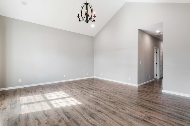 spare room with a chandelier, high vaulted ceiling, wood finished floors, and baseboards