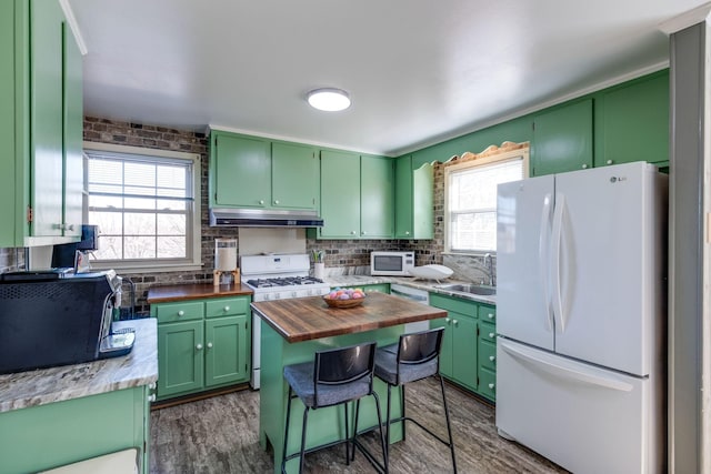 kitchen featuring white appliances, wooden counters, under cabinet range hood, and green cabinets