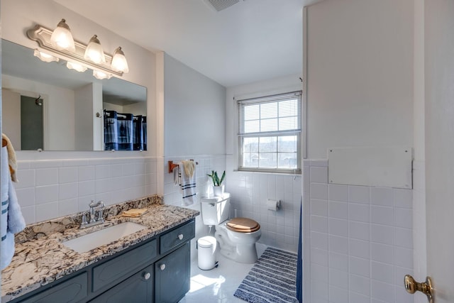 full bathroom with visible vents, toilet, a wainscoted wall, vanity, and tile walls