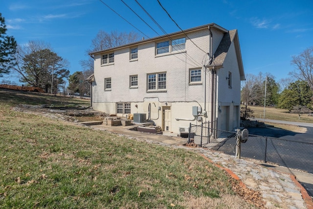 back of property featuring brick siding, an attached garage, central AC unit, fence, and driveway