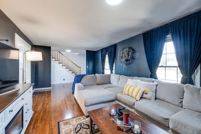 living room featuring stairs, dark wood-style flooring, and baseboards