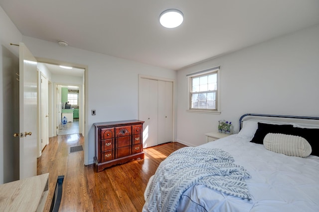 bedroom with a closet, multiple windows, visible vents, and wood finished floors