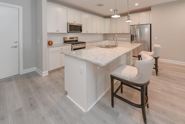 kitchen featuring visible vents, light wood finished floors, a sink, appliances with stainless steel finishes, and backsplash