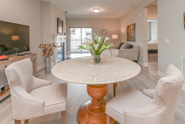 dining area featuring visible vents, light wood-style flooring, and baseboards