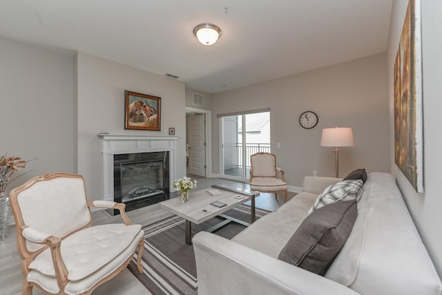 living room featuring a glass covered fireplace, baseboards, and visible vents