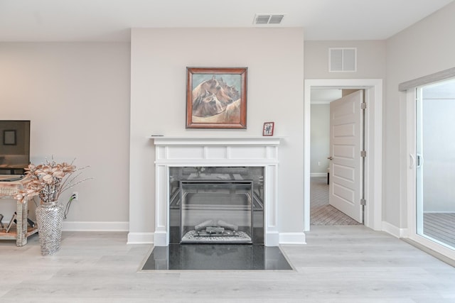 interior details with visible vents, a fireplace with flush hearth, and wood finished floors