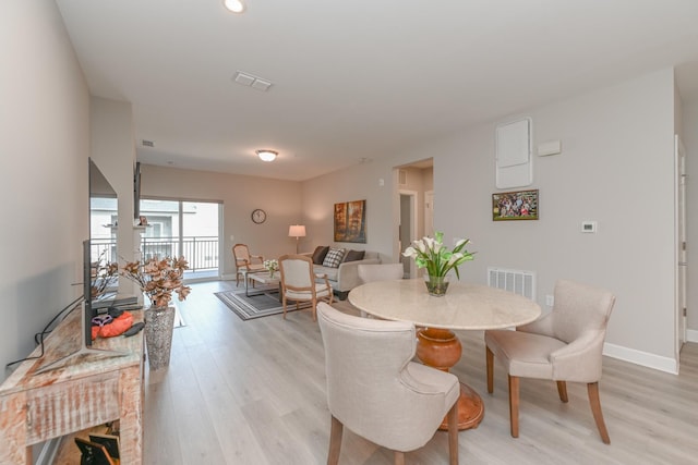 dining room with light wood-type flooring, visible vents, and baseboards