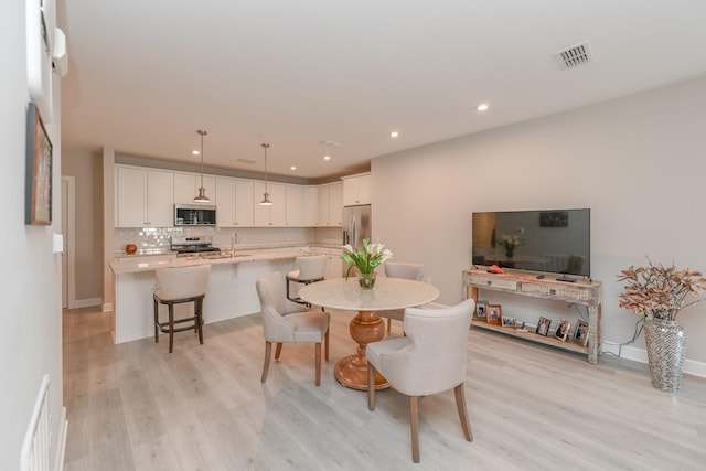 dining space with recessed lighting, visible vents, and light wood-style flooring