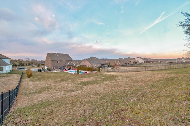 yard at dusk featuring a fenced backyard, a residential view, and a patio