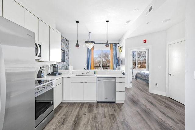 kitchen featuring stainless steel appliances, light countertops, white cabinetry, and a sink