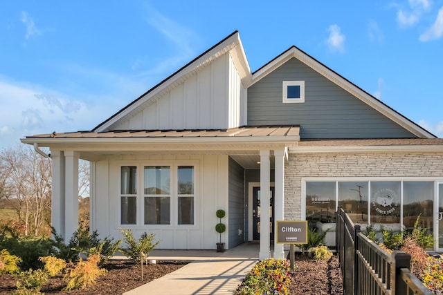 view of front facade with board and batten siding, a standing seam roof, metal roof, and stone siding