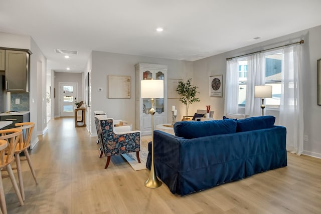 living area with light wood finished floors, recessed lighting, visible vents, and baseboards