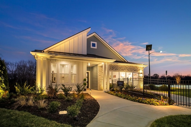 view of front of home with a standing seam roof, fence, metal roof, and board and batten siding