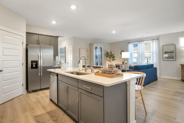 kitchen with stainless steel appliances, a sink, light countertops, and gray cabinetry