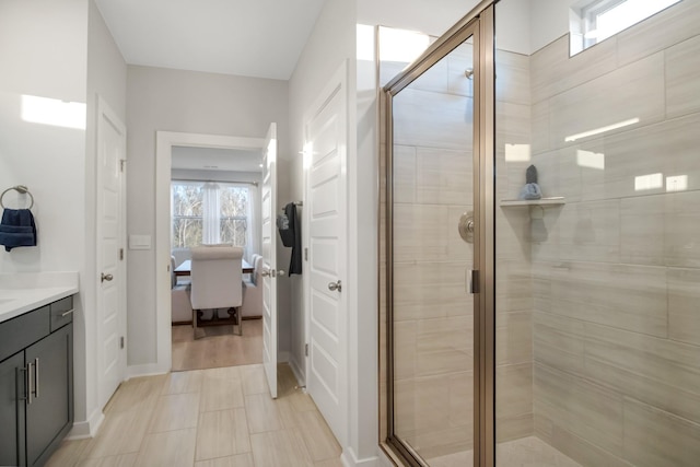 ensuite bathroom with ensuite bathroom, a stall shower, vanity, and baseboards