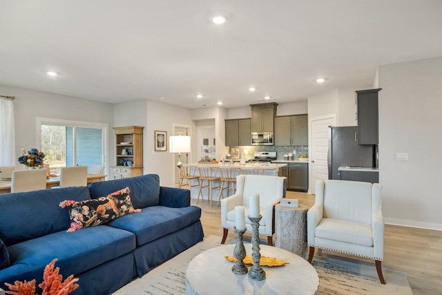 living area with light wood-style floors, baseboards, and recessed lighting