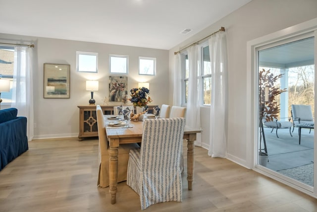 dining room with light wood-type flooring, visible vents, and baseboards