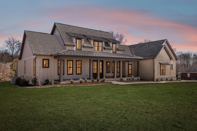 back of house featuring a shingled roof, a lawn, board and batten siding, a standing seam roof, and metal roof