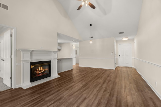 unfurnished living room with a glass covered fireplace, visible vents, ceiling fan, and wood finished floors