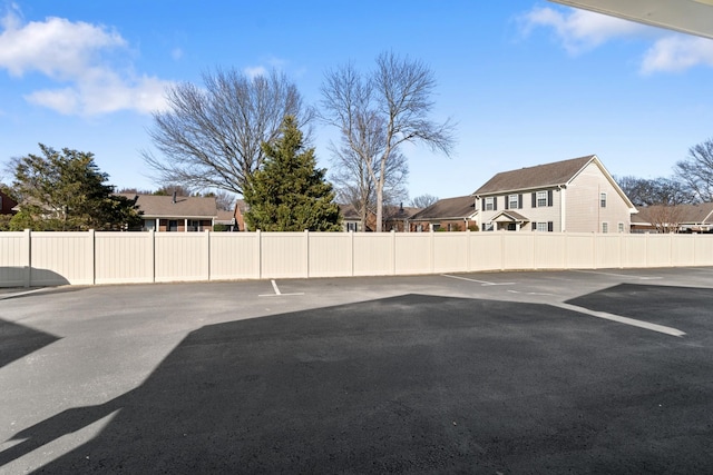 uncovered parking lot featuring fence and a residential view