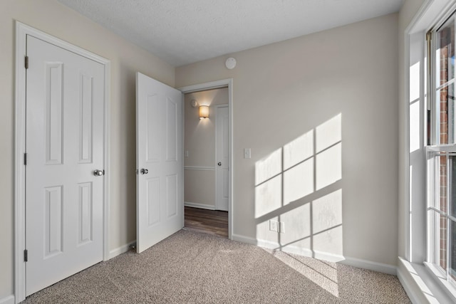 unfurnished bedroom featuring carpet floors, baseboards, and a textured ceiling