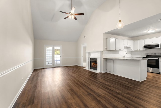 kitchen with appliances with stainless steel finishes, open floor plan, dark wood-type flooring, a peninsula, and backsplash