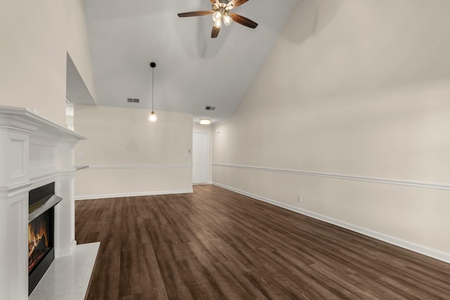 unfurnished living room with a warm lit fireplace, baseboards, visible vents, and dark wood-style flooring