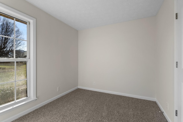 carpeted spare room featuring a textured ceiling and baseboards