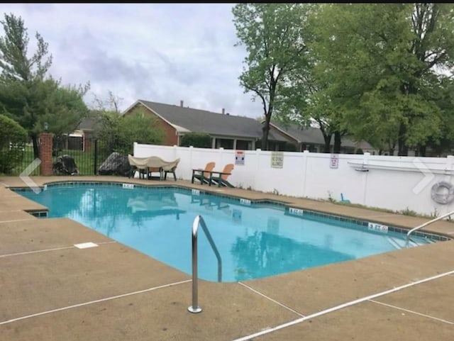 community pool with a patio area and fence